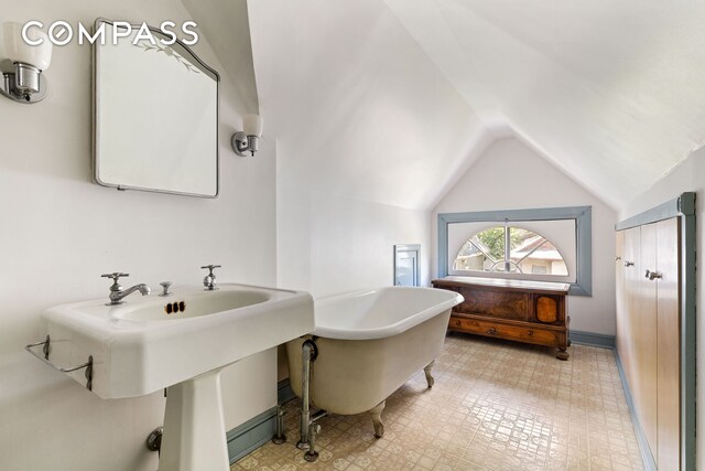 492 Westminster Rd, New York City, NY 11218 - full bathroom featuring a soaking tub, vaulted ceiling, tile patterned floors, and a sink