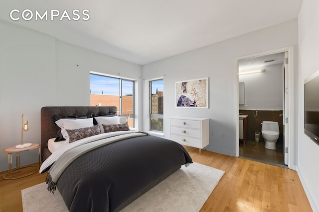 460 W 236th St Unit 65, New York City, NY 10463 - bedroom with light wood-type flooring, connected bathroom, and baseboards