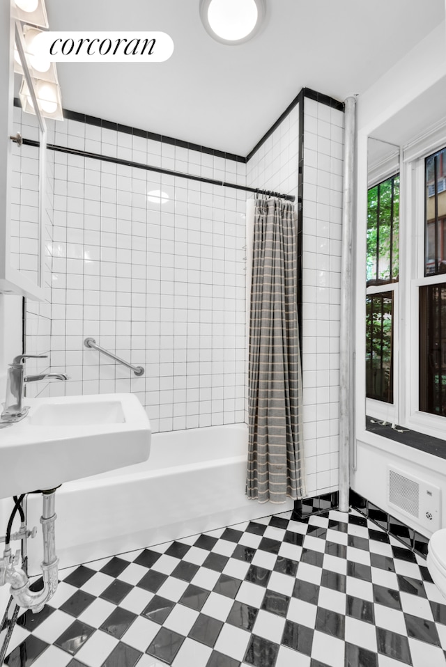 198 E 7th St Unit 1, New York City, NY 10009 - bathroom with tile patterned floors, shower / bath combo with shower curtain, toilet, and a sink