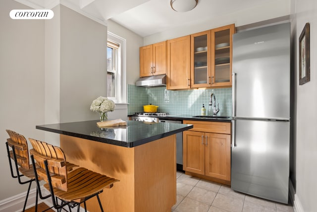 304 W 75th St Unit 9H, New York City, NY 10023 - kitchen featuring freestanding refrigerator, under cabinet range hood, a kitchen bar, backsplash, and glass insert cabinets