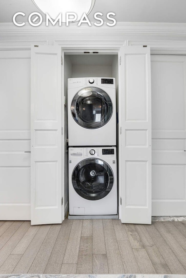 201 E 80th St Unit 16E, New York City, NY 10075 - laundry room with stacked washing machine and dryer, light wood finished floors, and crown molding