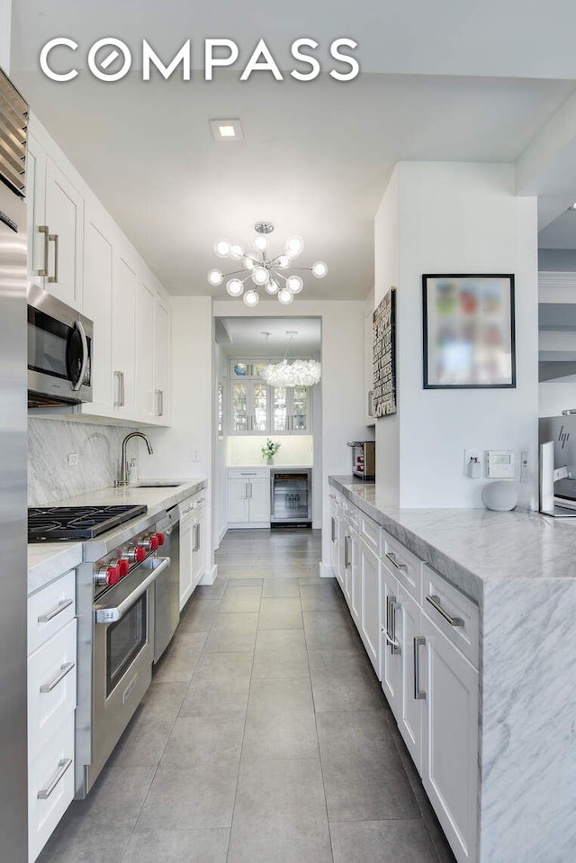 201 E 80th St Unit 16E, New York City, NY 10075 - kitchen featuring premium appliances, a chandelier, and white cabinetry