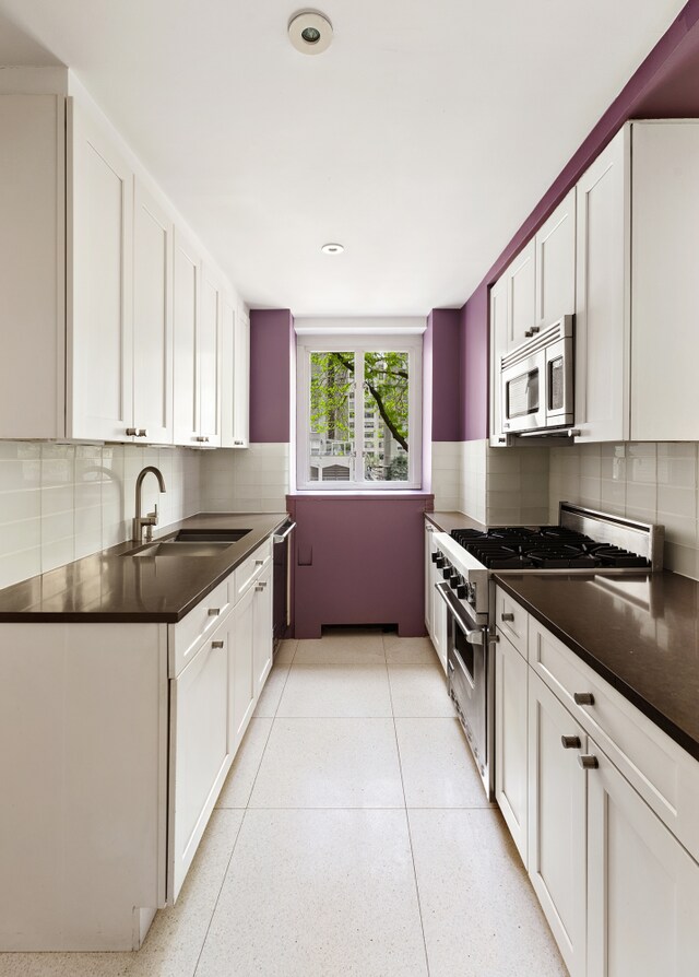 200 E 66th St Unit E307, New York City, NY 10065 - kitchen with appliances with stainless steel finishes, dark countertops, decorative backsplash, and white cabinetry