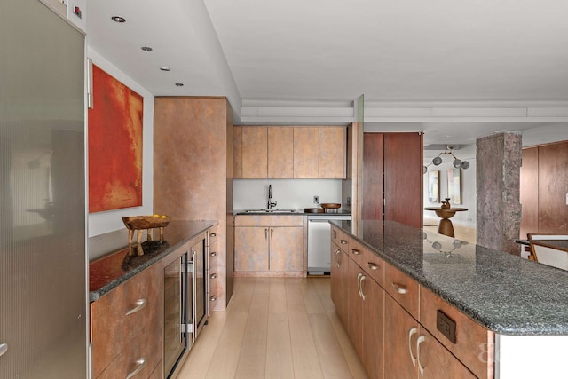 118 E 60th St Unit 33/32Duplex, New York City, NY 10022 - kitchen featuring a kitchen island, light wood-style floors, brown cabinets, stainless steel dishwasher, and dark stone countertops