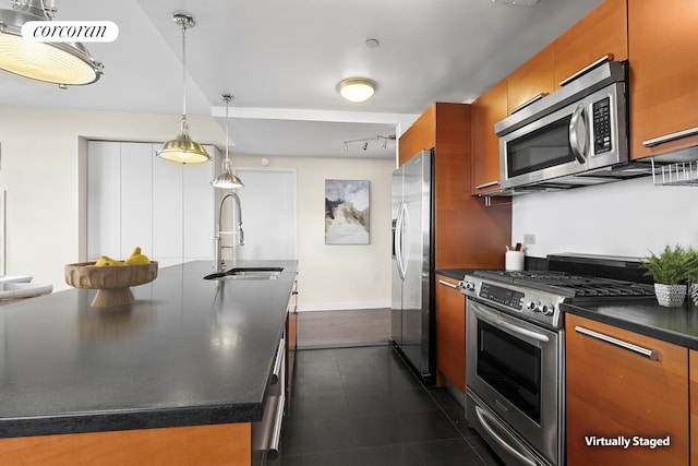 1485 5th Ave Unit 19C, New York City, NY 10035 - kitchen featuring appliances with stainless steel finishes, dark countertops, brown cabinets, a center island with sink, and decorative light fixtures