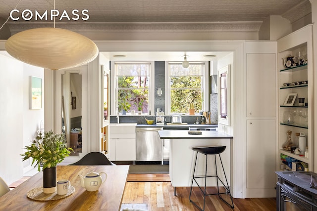 159 Coffey St, New York City, NY 11231 - kitchen featuring stainless steel dishwasher, white cabinetry, wood finished floors, a peninsula, and a breakfast bar