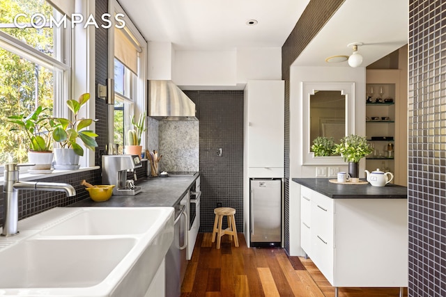 159 Coffey St, New York City, NY 11231 - kitchen with a sink, wall chimney range hood, dark wood finished floors, white cabinets, and backsplash