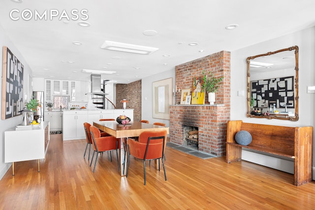 120 W 20th St Ph, Ph, New York City, NY 10011 - dining area with light wood-style floors, a brick fireplace, recessed lighting, and stairs