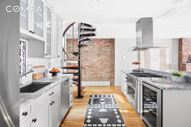 120 W 20th St Ph, Ph, New York City, NY 10011 - kitchen featuring island range hood, beverage cooler, stainless steel appliances, light wood finished floors, and brick wall