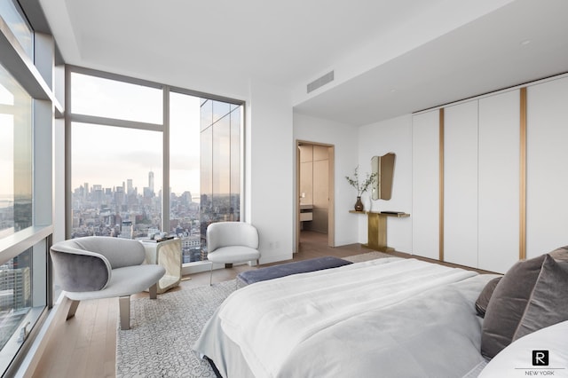 23 E 22nd St Unit 55, New York City, NY 10010 - bedroom featuring multiple windows, wood finished floors, a skyline view, and floor to ceiling windows