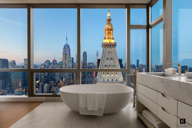 23 E 22nd St Unit 55, New York City, NY 10010 - bathroom featuring a skyline view, a freestanding tub, vanity, a wall of windows, and wood finished floors
