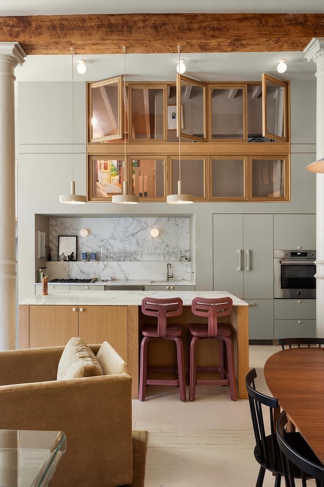 132 Greene St Unit 3R, New York City, NY 10012 - kitchen featuring oven, tasteful backsplash, a kitchen breakfast bar, light countertops, and modern cabinets