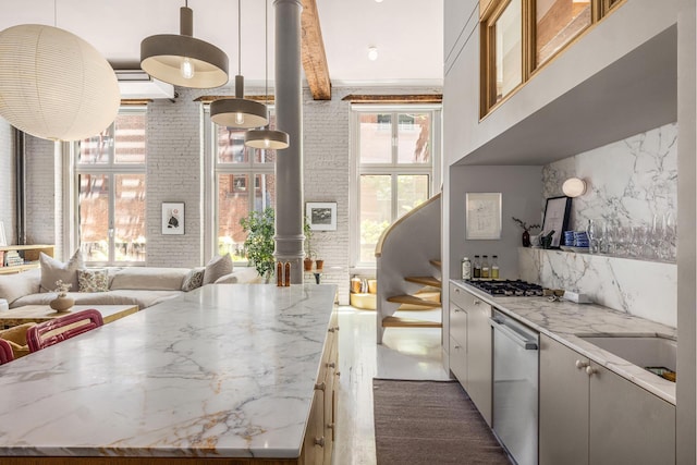 132 Greene St Unit 3R, New York City, NY 10012 - kitchen featuring a high ceiling, stainless steel appliances, open floor plan, light stone counters, and hanging light fixtures