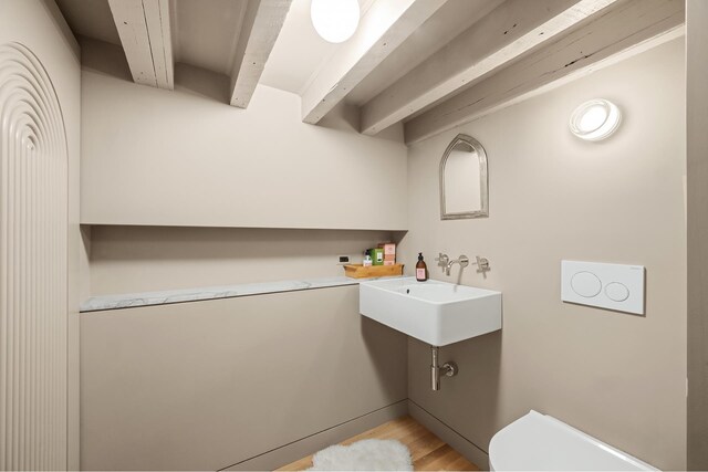 132 Greene St Unit 3R, New York City, NY 10012 - bathroom featuring beam ceiling and wood finished floors