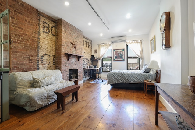940 Fulton St Unit 3B, New York City, NY 11238 - bedroom with wood-type flooring, a brick fireplace, brick wall, a wall mounted air conditioner, and recessed lighting