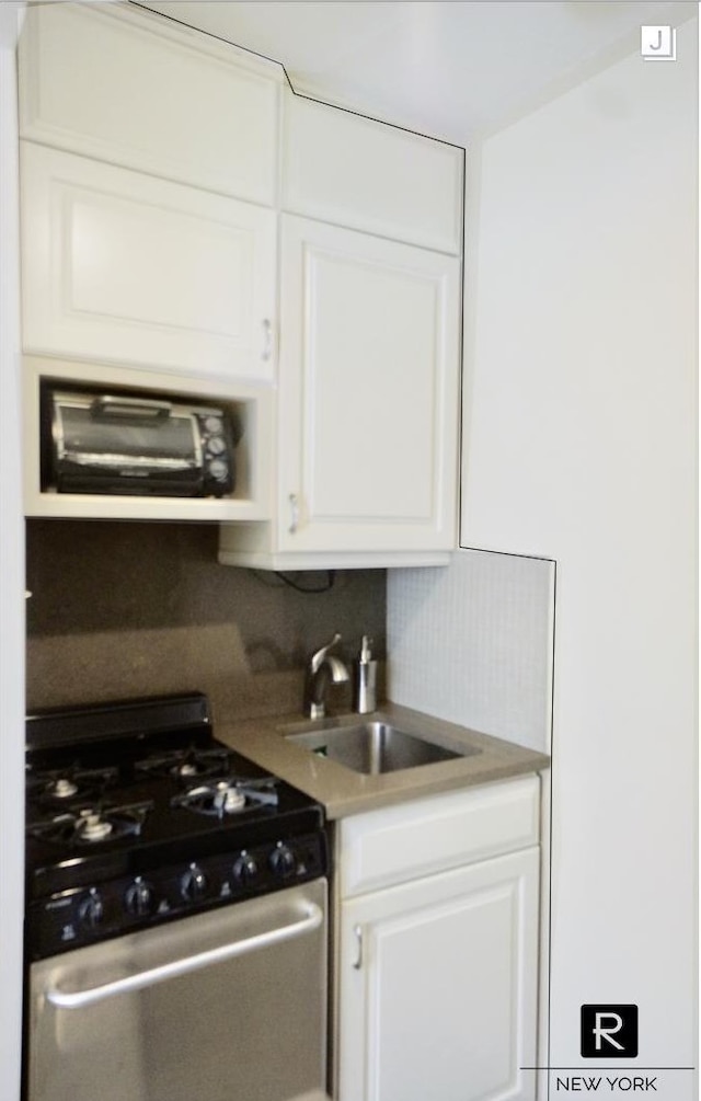 233 E 69th St Unit 3-O, New York City, NY 10021 - kitchen with stainless steel range with gas stovetop, a sink, white cabinets, and backsplash