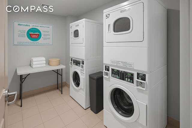 40 W 116th St Unit B302, New York City, NY 10026 - communal laundry room with stacked washer and clothes dryer, baseboards, and light tile patterned floors