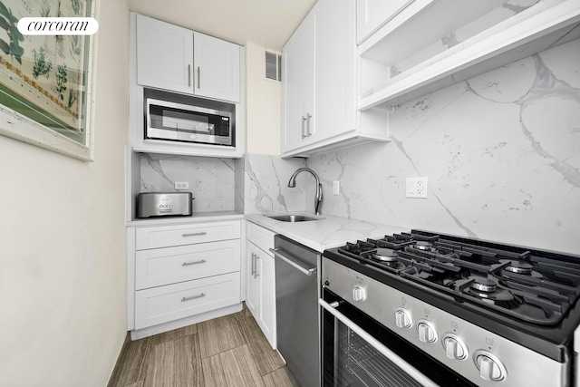 201 E 37th St Unit 4F, New York City, NY 10016 - kitchen featuring appliances with stainless steel finishes, a sink, white cabinets, backsplash, and light stone countertops