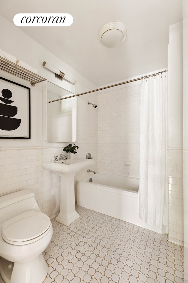 99 Jane St Unit 2J, New York City, NY 10014 - bathroom with shower / bath combo, toilet, tile walls, and wainscoting