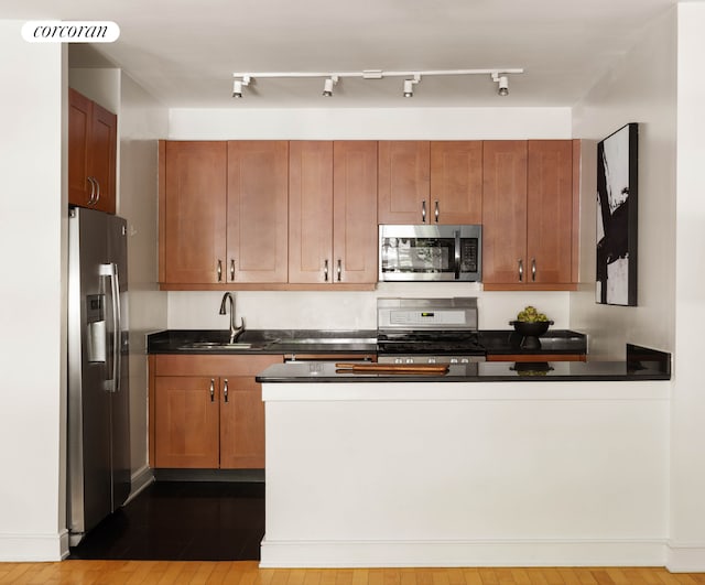 99 Jane St Unit 2J, New York City, NY 10014 - kitchen with stainless steel appliances, a sink, dark countertops, and brown cabinets