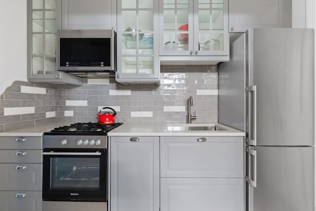 146 St Johns Place, New York City, NY 11217 - kitchen featuring stainless steel appliances, a sink, light countertops, decorative backsplash, and glass insert cabinets