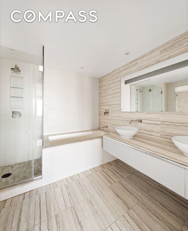 322 W 57th St Unit 33U, New York City, NY 10019 - full bathroom with double vanity, a garden tub, a shower stall, and decorative backsplash