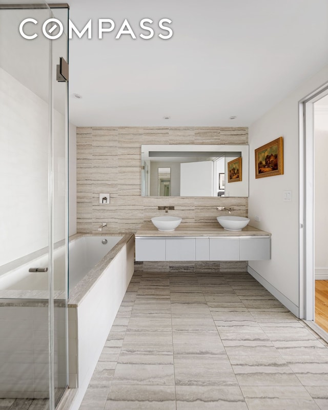 322 W 57th St Unit 33U, New York City, NY 10019 - bathroom with double vanity, a shower stall, and a garden tub