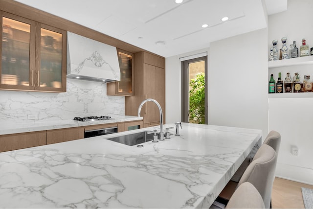 40 Bleecker St Unit 3H, New York City, NY 10012 - kitchen featuring a sink, custom exhaust hood, brown cabinets, stainless steel gas cooktop, and light stone counters