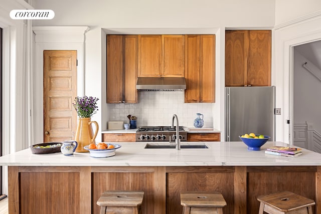 151 Herkimer St, New York City, NY 11216 - kitchen with freestanding refrigerator, under cabinet range hood, backsplash, brown cabinets, and a breakfast bar