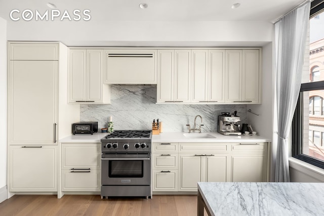 76 Schermerhorn St Unit 4C, New York City, NY 11201 - kitchen featuring high end stove, a sink, decorative backsplash, and light wood-style floors
