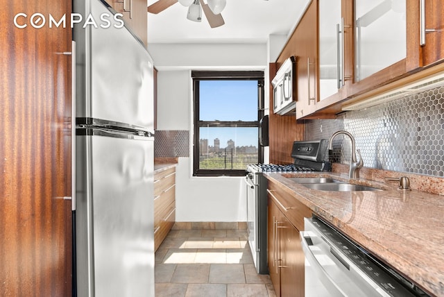 345 W 145th St Unit 8C3, New York City, NY 10031 - kitchen featuring appliances with stainless steel finishes, brown cabinets, ceiling fan, decorative backsplash, and light stone counters