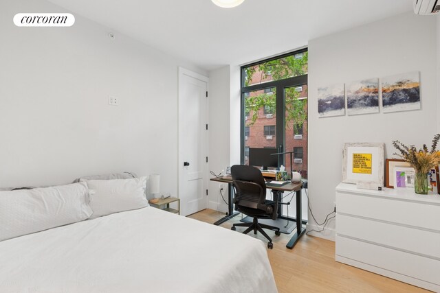 112 Fleet Pl Unit 2A, New York City, NY 11201 - bedroom with an AC wall unit, light wood-style floors, and an office area