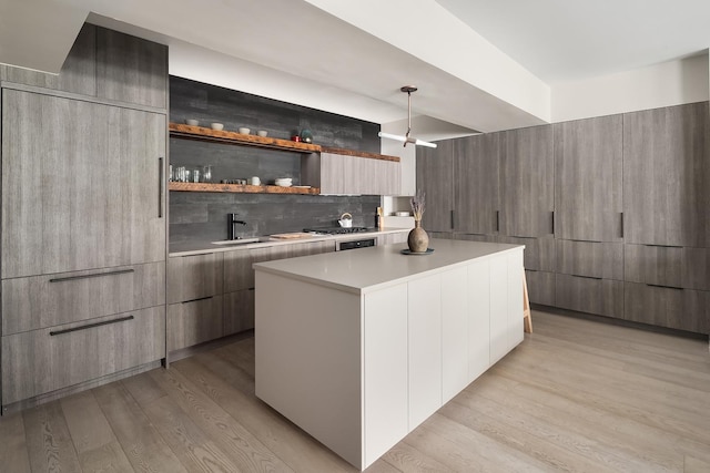 231 10th Ave Unit 5A, New York City, NY 10011 - kitchen featuring modern cabinets, light wood-style floors, a center island, light countertops, and a sink