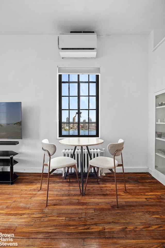 25 Tudor City Pl Unit 2101, New York City, NY 10017 - dining area with radiator heating unit, a wall unit AC, wood finished floors, and baseboards