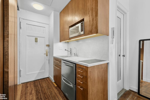 25 Tudor City Pl Unit 2101, New York City, NY 10017 - kitchen featuring stainless steel appliances, a sink, brown cabinets, light countertops, and dark wood-style floors