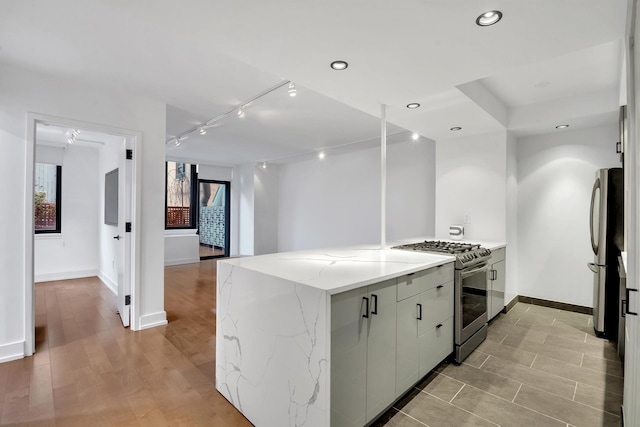 199 Bowery Unit 2D, New York City, NY 10003 - kitchen featuring stainless steel appliances, baseboards, light stone counters, recessed lighting, and track lighting