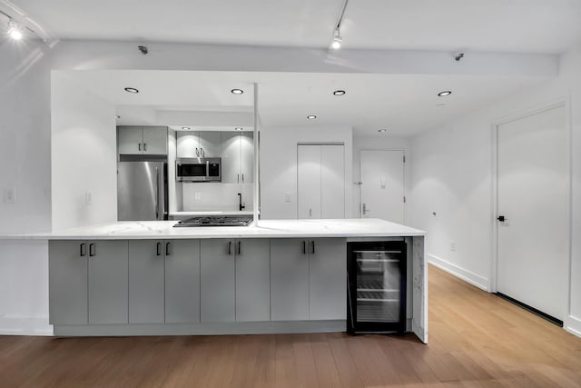 199 Bowery Unit 2D, New York City, NY 10003 - kitchen featuring appliances with stainless steel finishes, gray cabinetry, wine cooler, rail lighting, and light wood-style floors