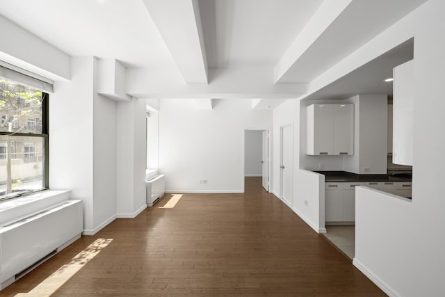 99 John St Unit 1405, New York City, NY 10038 - kitchen featuring hardwood / wood-style floors, dark countertops, white cabinetry, baseboards, and radiator