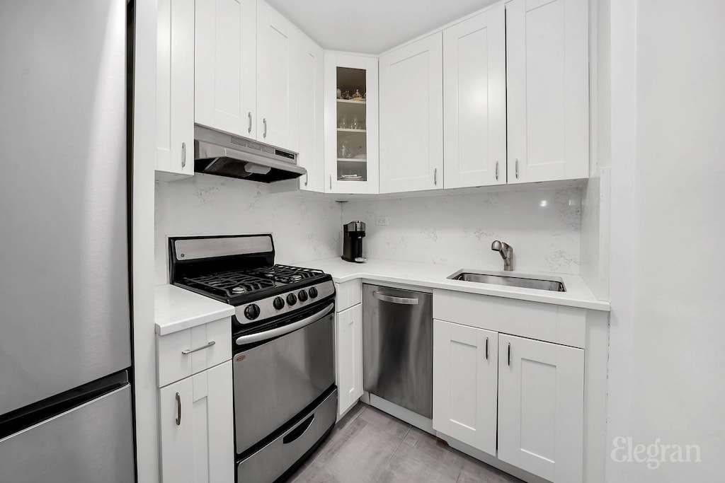 305 E 40th St Unit 10W, New York City, NY 10016 - kitchen featuring stainless steel appliances, under cabinet range hood, a sink, and white cabinetry