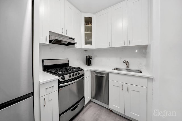 305 E 40th St Unit 10W, New York City, NY 10016 - kitchen featuring stainless steel appliances, under cabinet range hood, a sink, and white cabinetry