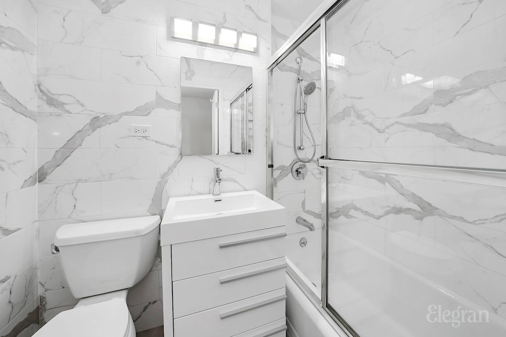 305 E 40th St Unit 10W, New York City, NY 10016 - bathroom with tile walls, combined bath / shower with glass door, vanity, and toilet