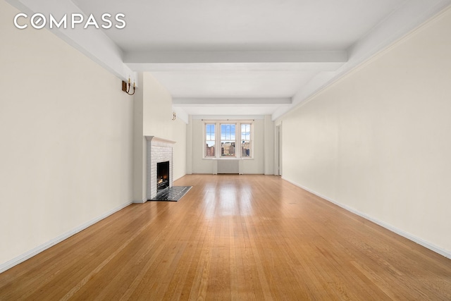 45 Christopher St Unit 12/14F, New York City, NY 10014 - unfurnished living room with radiator heating unit, beamed ceiling, a fireplace, light wood-type flooring, and baseboards