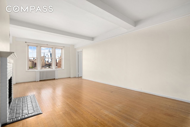 45 Christopher St Unit 12/14F, New York City, NY 10014 - unfurnished living room with radiator, beamed ceiling, a fireplace, wood-type flooring, and baseboards