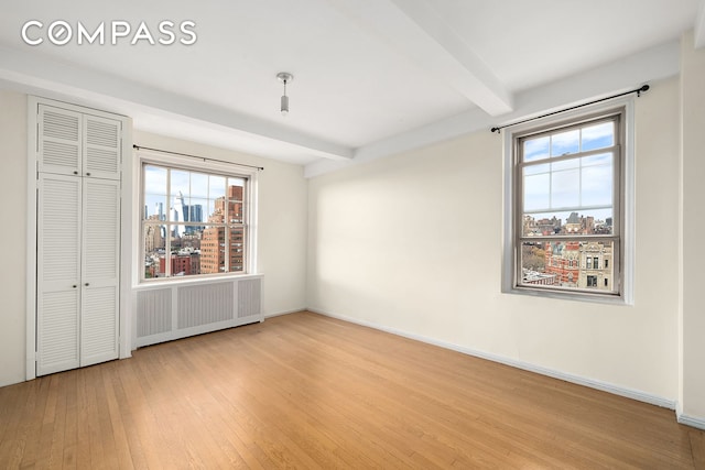 45 Christopher St Unit 12/14F, New York City, NY 10014 - unfurnished bedroom featuring beamed ceiling, wood finished floors, a city view, baseboards, and a closet