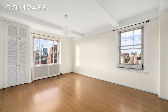45 Christopher St Unit 12/14F, New York City, NY 10014 - unfurnished bedroom featuring radiator heating unit, wood-type flooring, beamed ceiling, baseboards, and a closet