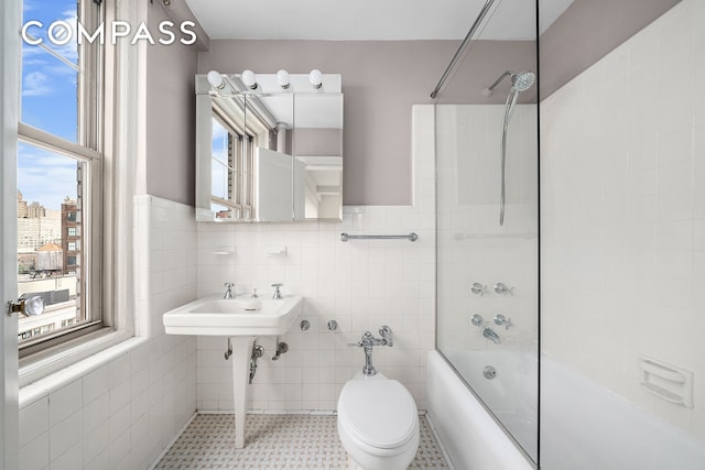 45 Christopher St Unit 12/14F, New York City, NY 10014 - bathroom featuring tile walls, shower / washtub combination, plenty of natural light, a sink, and wainscoting