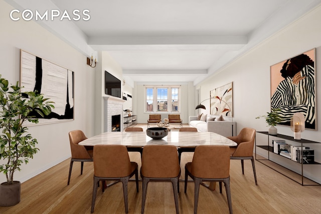 45 Christopher St Unit 12/14F, New York City, NY 10014 - dining area featuring light wood-style floors, a fireplace, baseboards, and beamed ceiling