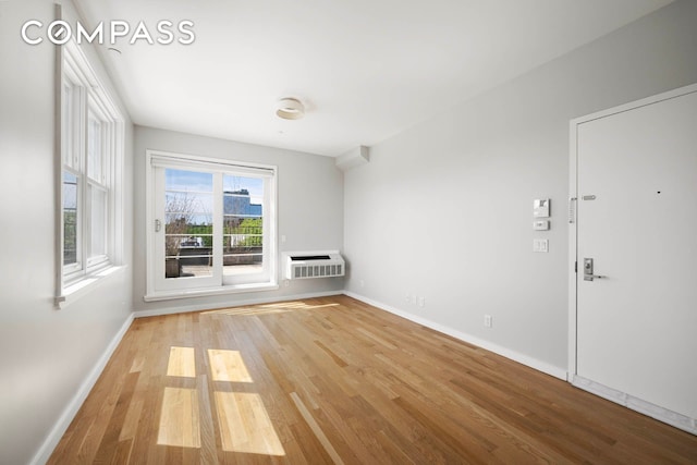 195 Hawthorne St Unit 5E, New York City, NY 11225 - spare room featuring wood finished floors, baseboards, and a wall mounted air conditioner