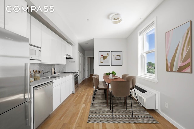 195 Hawthorne St Unit 5E, New York City, NY 11225 - kitchen with appliances with stainless steel finishes, white cabinets, under cabinet range hood, a sink, and light wood-type flooring