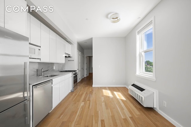 195 Hawthorne St Unit 5E, New York City, NY 11225 - kitchen with stainless steel appliances, a sink, white cabinetry, under cabinet range hood, and light wood-type flooring